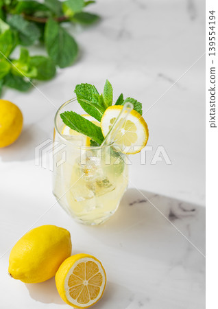 Refreshing lemon mint drink with ice in glass, homemade summer lemonade on marble background 139554194