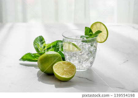 A fresh mojito with lime, mint and ice in glass. Citrus lemonade or cocktail on a marble table A fresh mojito with lime, mint and ice in glass. Citrus lemonade or cocktail on a marble table 139554198