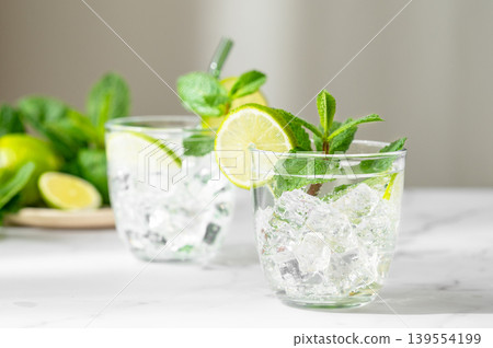 A fresh mojito with lime, mint and ice in glasses. Citrus lemonade or cocktail on a marble table 139554199