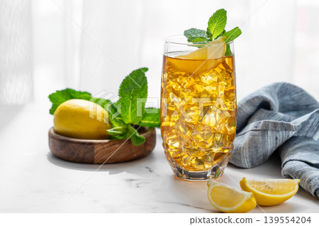 Iced tea with lemon and mint in a glass on a marble countertop with citrus fruits 139554204