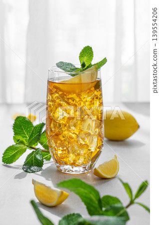 Iced tea with lemon and mint in a glass on a concrete countertop with citrus fruits Iced tea with lemon and mint in a glass on a concrete countertop with citrus fruits 139554206