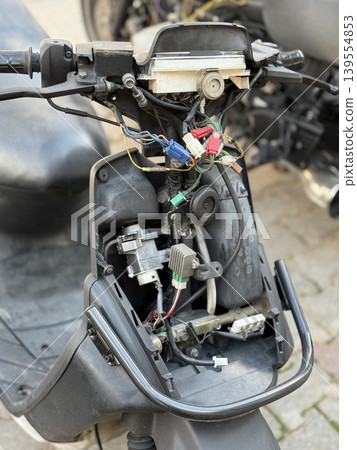 Motorcycle repair with exposed wiring and parts, showing internal mechanisms and components Motorcycle repair with exposed wiring and parts, showing internal mechanisms and components 139554853