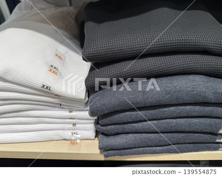 Folded clothes in assorted sizes on shelf display, showcasing retail organization background Folded clothes in assorted sizes on shelf display, showcasing retail organization background 139554875
