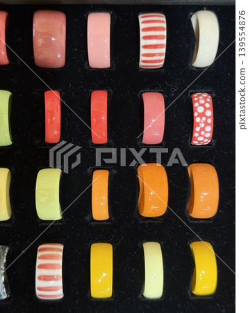 Colorful ceramic rings neatly arranged on black velvet background showcase vibrant patterns Colorful ceramic rings neatly arranged on black velvet background showcase vibrant patterns 139554876