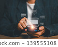 Close-up of hands using a smartphone with digital chat bubbles, symbolizing online communication and connectivity. 139555108