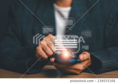 Close-up of hands using a smartphone with digital chat bubbles, symbolizing online communication and connectivity. Close-up of hands using a smartphone with digital chat bubbles, symbolizing online communication and connectivity. 139555108