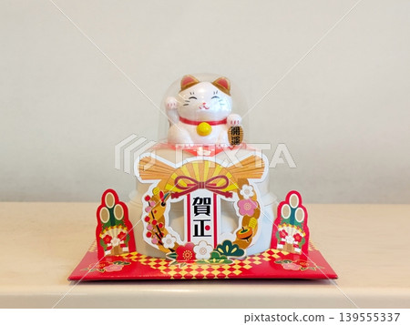 A charming New Year's decoration featuring a lucky cat sitting on top of a Kagami Mochi (rice cake offering). A charming New Year's decoration featuring a lucky cat sitting on top of a Kagami Mochi (rice cake offering). 139555337