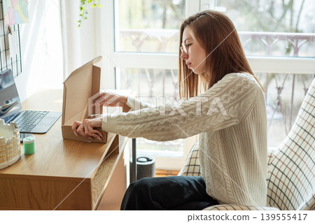 Woman opening a cardboard box Woman opening a cardboard box 139555417
