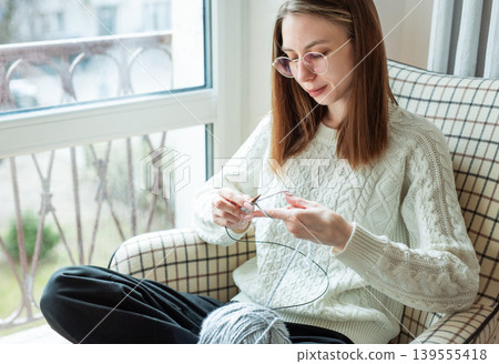 Woman knitting new sweater with gray yarn at home Woman knitting new sweater with gray yarn at home 139555418