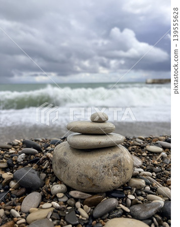 A balanced pyramid of smooth stones against the backdrop of a raging sea 139555628