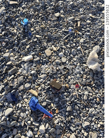 The pebble beach is strewn with plastic waste washed ashore by the sea. concept of environmental protection The pebble beach is strewn with plastic waste washed ashore by the sea. concept of environmental protection 139555632