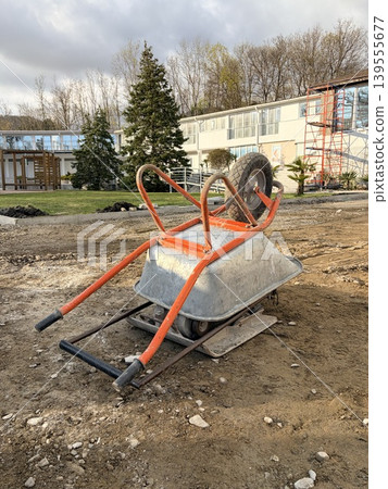 A construction wheelbarrow with one wheel for transporting building materials is turned upside down. A construction wheelbarrow with one wheel for transporting building materials is turned upside down. 139555677