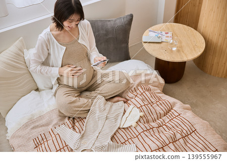 A pregnant woman places her hand on her stomach while looking at an ultrasound image. A pregnant woman places her hand on her stomach while looking at an ultrasound image. 139555967
