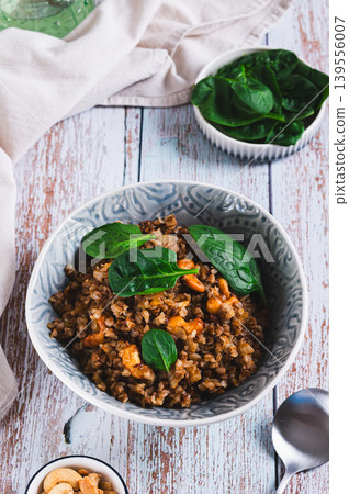 Dietary boiled buckwheat with nuts and spinach on the table vertical view Dietary boiled buckwheat with nuts and spinach on the table vertical view 139556007