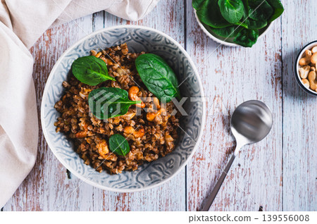 Vegetarian buckwheat with cashews and spinach in a bowl on the table top view Vegetarian buckwheat with cashews and spinach in a bowl on the table top view 139556008