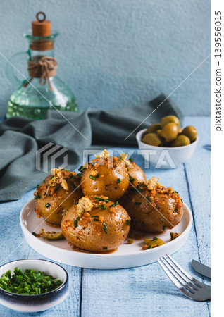 Baked new potatoes with herbs and olives on a plate on the table vertical view Baked new potatoes with herbs and olives on a plate on the table vertical view 139556015