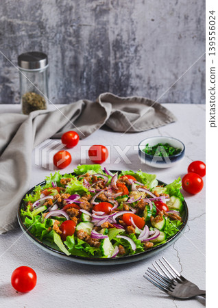A delicious salad with minced meat, tomatoes, cucumber, onion and lettuce on a plate vertical view A delicious salad with minced meat, tomatoes, cucumber, onion and lettuce on a plate vertical view 139556024
