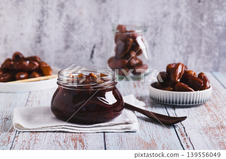 Sweet date marmalade in a jar and fruit in a bowl on a table 139556049
