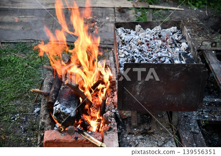 in a summer evening, two men in their forties prepares a barbecue for friends gathered around a table in a summer evening, two men in their forties prepares a barbecue for friends gathered around a table 139556351