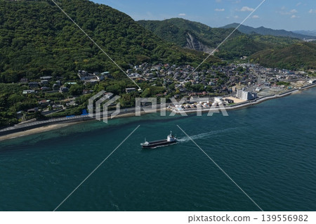 一張空拍照片,捕捉到一艘貨船駛過關門海峽以及下關市沿海的城市景觀。 一張空拍照片,捕捉到一艘貨船駛過關門海峽以及下關市沿海的城市景觀。 139556982