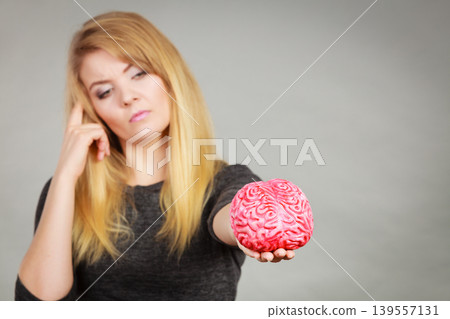 Woman thinking and holding fake brain Woman thinking and holding fake brain 139557131