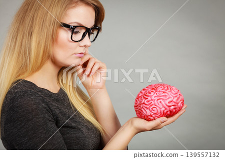 Woman thinking and holding fake brain 139557132