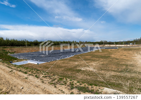 Workers prepare land for a new landfill. A black liner covers the area as equipment is set up. The site is located in a rural setting Workers prepare land for a new landfill. A black liner covers the area as equipment is set up. The site is located in a rural setting 139557267