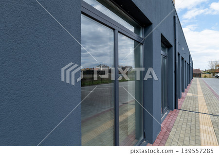 Workers have completed the installation of new windows in a gray building. The windows reflect the sky and surrounding area Workers have completed the installation of new windows in a gray building. The windows reflect the sky and surrounding area 139557285