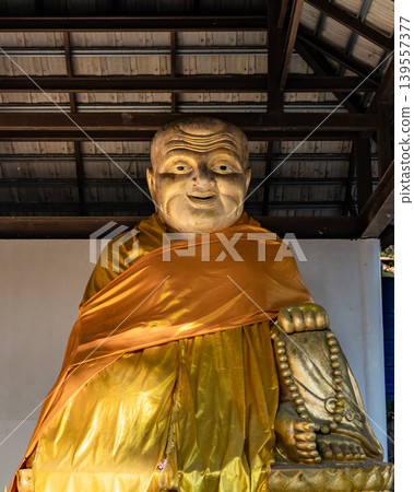 Quiet pavilion with large seated monk figure creates reflective stop for visitors exploring historic countryside landmarks, spiritual heritage sites, tropical cultural travel experiences. Quiet pavilion with large seated monk figure creates reflective stop for visitors exploring historic countryside landmarks, spiritual heritage sites, tropical cultural travel experiences. 139557377
