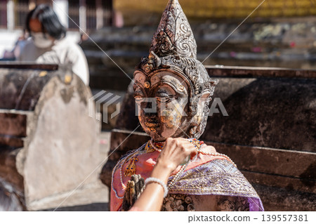Weathered female guardian figure stands within a sacred temple site surrounded by historic stone structures and cultural heritage architecture. 139557381
