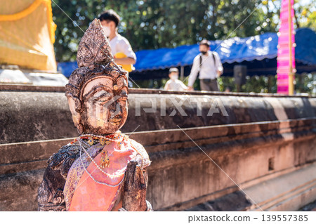 Weathered female guardian figure stands within a sacred temple site surrounded by historic stone structures and cultural heritage architecture. 139557385