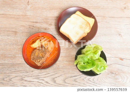 beef curry or Mussamun Indian food with slice potato and tomato on bowl eat couple fresh cos lettuce salad and grilled butter toast bread beef curry or Mussamun Indian food with slice potato and tomato on bowl eat couple fresh cos lettuce salad and grilled butter toast bread 139557639