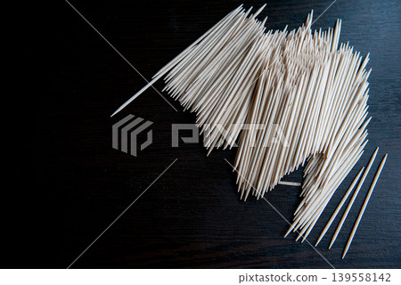 Wooden toothpicks scattered on dark textured surface 139558142