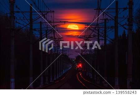 Red full moon rising over railroad tracks at twilight Red full moon rising over railroad tracks at twilight 139558243
