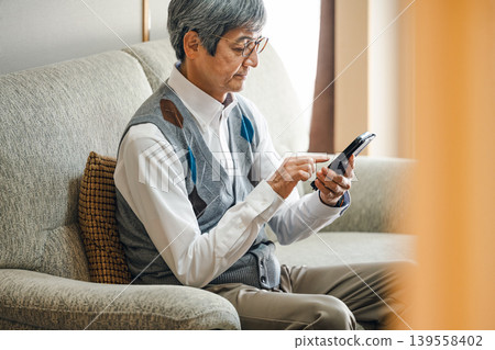 老人在家沙發上看智慧型手機 老人在家沙發上看智慧型手機 139558402