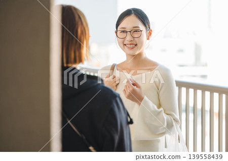 A young woman chatting with her fellow mothers in the hallway of an apartment building. A young woman chatting with her fellow mothers in the hallway of an apartment building. 139558439
