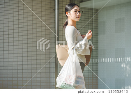 A young woman returning to her apartment after shopping. A young woman returning to her apartment after shopping. 139558443