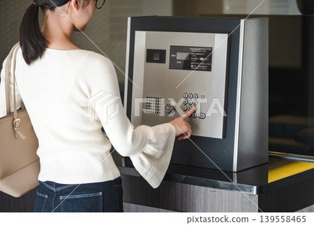 一名年輕女子正在操作公寓大樓的自動計時器。 一名年輕女子正在操作公寓大樓的自動計時器。 139558465