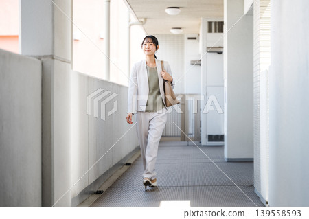 一位身穿職業套裝的年輕女子離開公寓去上班。 一位身穿職業套裝的年輕女子離開公寓去上班。 139558593