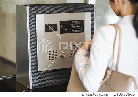 A woman presses the automatic lock button on the apartment building. 139558600