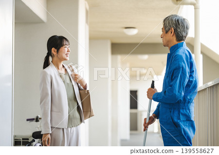 公寓大樓的走廊裡,一位住戶和一位樓管正在交談。 公寓大樓的走廊裡,一位住戶和一位樓管正在交談。 139558627