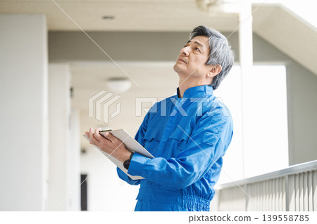 一位資深男性樓宇管理員正在檢查公寓大樓內的設施。 一位資深男性樓宇管理員正在檢查公寓大樓內的設施。 139558785