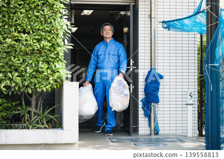 一位公寓大樓的高級男性管理員正在倒垃圾 一位公寓大樓的高級男性管理員正在倒垃圾 139558813