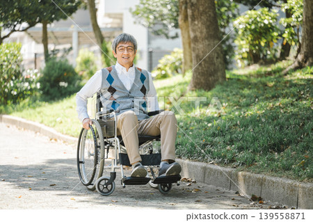 一位坐在輪椅上的老人在公園裡漫步。 一位坐在輪椅上的老人在公園裡漫步。 139558871