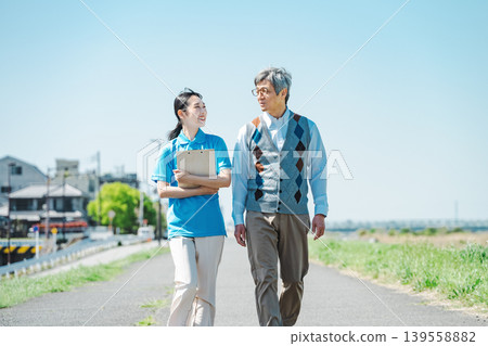 一位護理員和一位老人沿著河岸散步 139558882