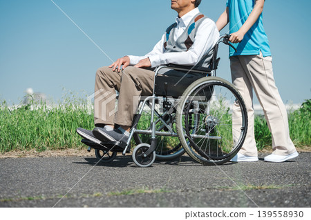 Image of a senior male caregiver taking a stroll in a wheelchair. 139558930