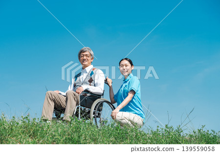 一位護理人員和一位坐在輪椅上的老人在公園散步。 139559058