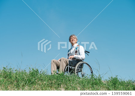 一位坐在輪椅上的老人沿著河岸漫步。 一位坐在輪椅上的老人沿著河岸漫步。 139559061