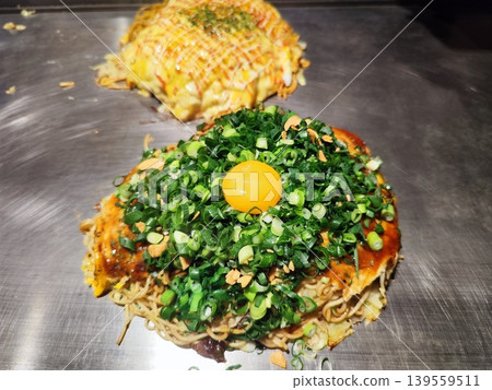 Hiroshima-style okonomiyaki topped with plenty of green onions and egg yolk Hiroshima-style okonomiyaki topped with plenty of green onions and egg yolk 139559511