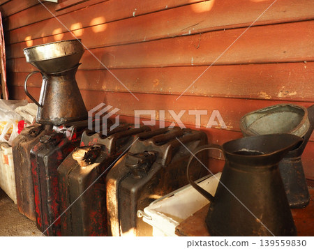 Fuel jerrycan rusty metal container funnel storage vintage old worn equipment in shed with warm light and texture Fuel jerrycan rusty metal container funnel storage vintage old worn equipment in shed with warm light and texture 139559830